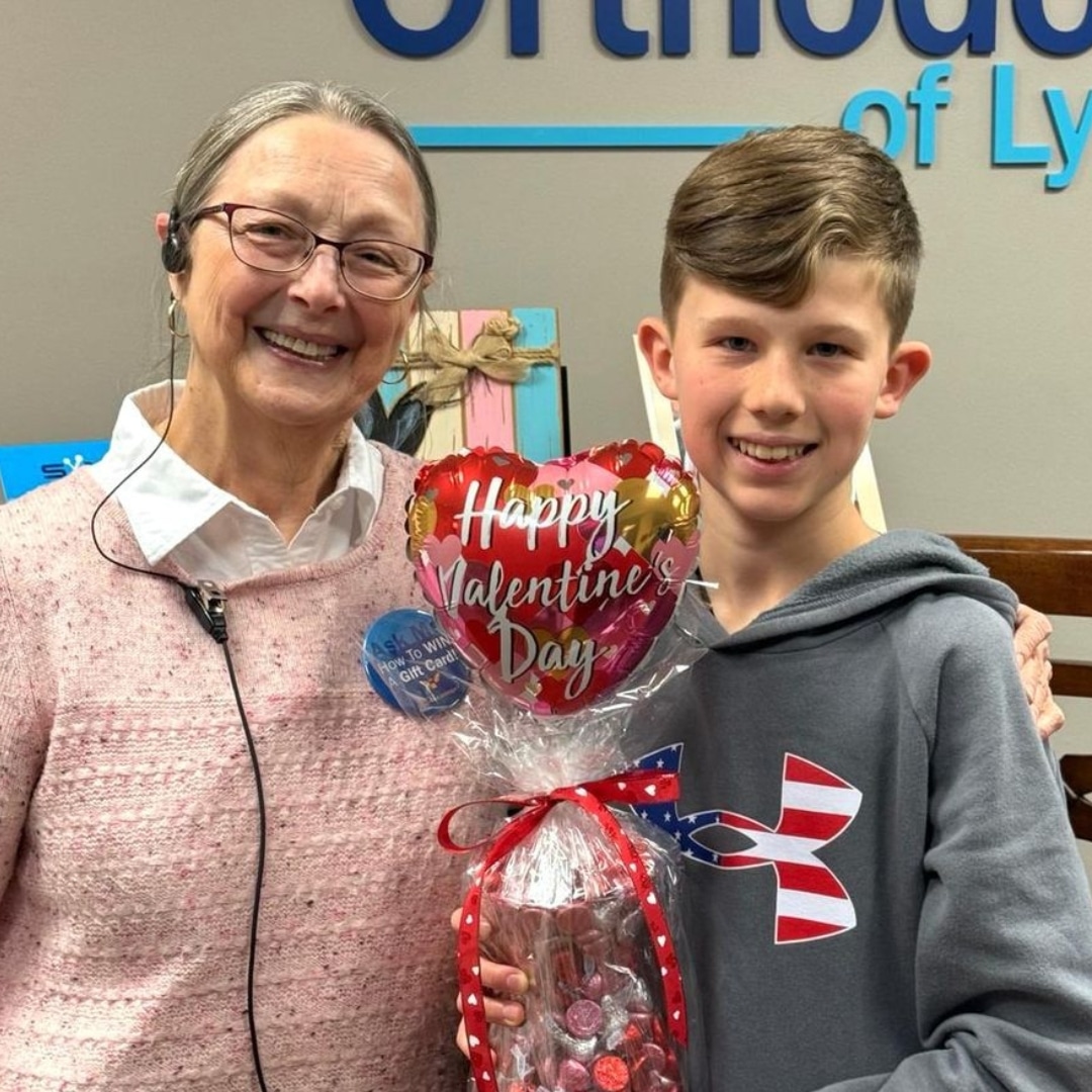 App-ortho-winner-valentines-day-camden Orthodontic patient smiling at office with valentine's day balloon