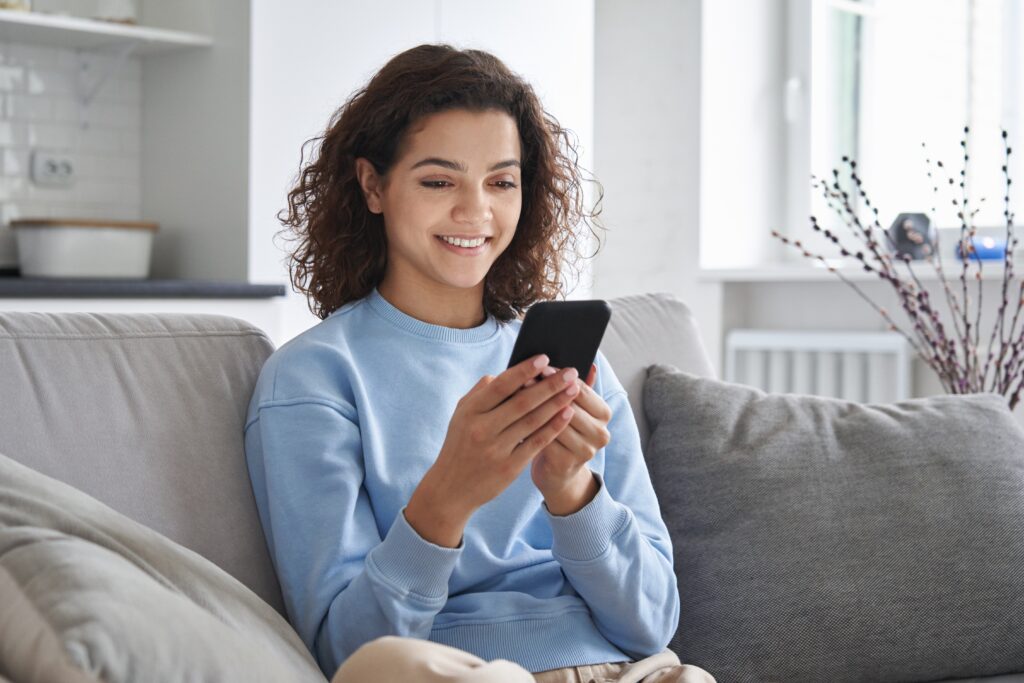 Happy hispanic teen girl holding cell phone using smartphone at home. Patient forms