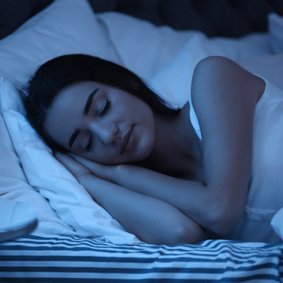 Help improve your sleep: why it matters and how we assist 11 Woman sleeping in a bed on her side with hands under her cheek, representing sleep help
